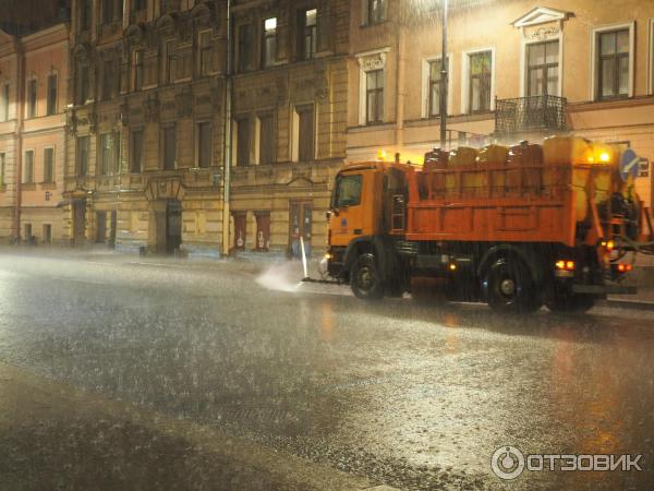 машина поливалка после праздника во время дождя